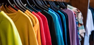 Färgglada tröjor på klädställning i butik